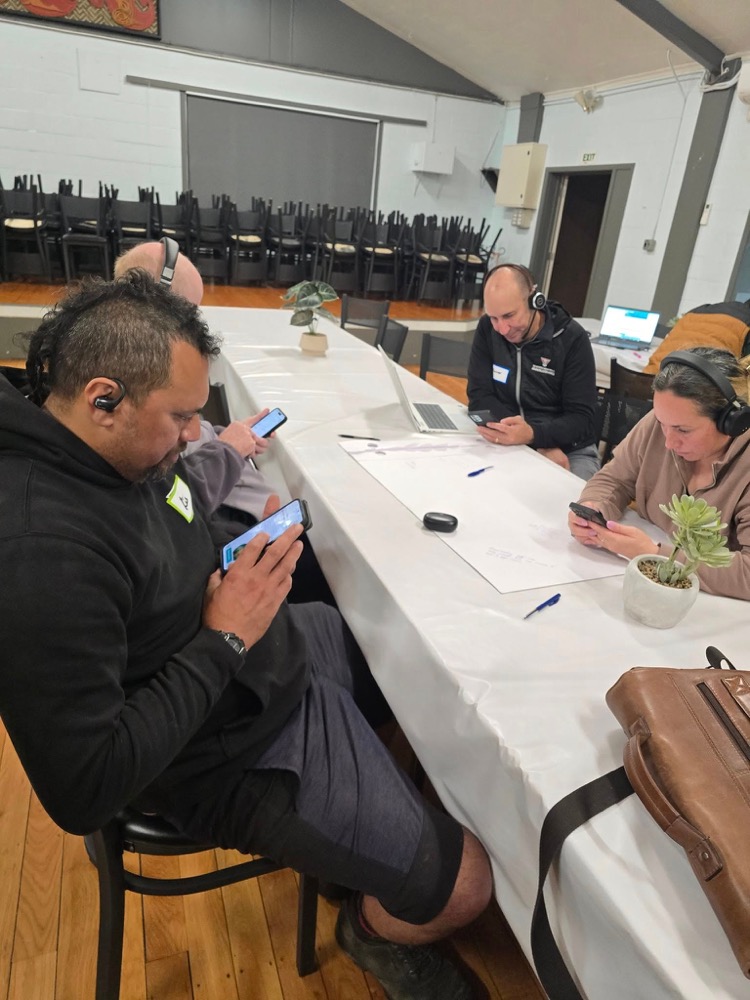Workshop participants testing the Mana Ako app with headphones